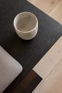 Ceramic cup with a speckled design on a dark wooden table, minimalist interior design.