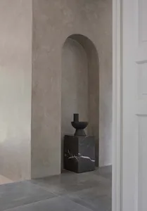 A modern minimalist living room featuring a single piece of furniture made from dark concrete, positioned against a plain con