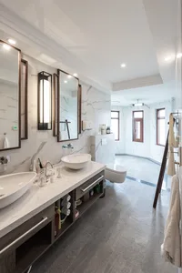 Modern bathroom with marble tiles, two sinks, and a toilet.