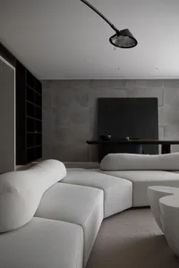 A modern living room with grey concrete walls, a minimalist sofa, and a marble coffee table.