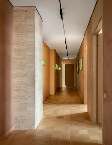 A modern, minimalist corridor with wooden flooring, green spherical lights, and framed artwork.