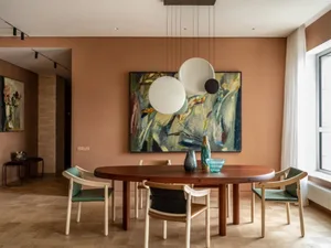 A modern dining room with minimalist art on the wall, a wooden dining table, and green chairs.