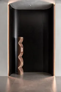 A modern entryway featuring black wooden panels and a sculptural wooden piece with wave-like patterns.