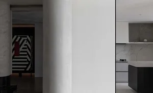 Modern interior design featuring a kitchen with marble countertops and white cabinets.