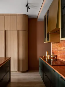 A modern kitchen with wooden cabinets, metallic accents, and a marble countertop.