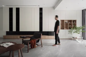 A modern living room features concrete walls and floor tiles, with minimalistic furniture and a large floor lamp.