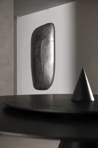 A metallic, minimalist decorative object with a futuristic design.
