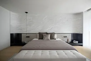 A minimalist bedroom with a marble-patterned wall, a large bed, and a tufted bench.
