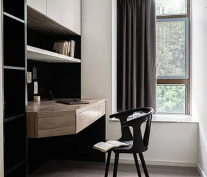 A tidy minimalist room with a modern desk area featuring wooden elements and a black chair.