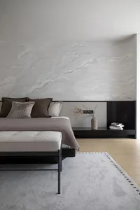 A modern bedroom with neutral-toned walls, bedding, and furniture, featuring a minimalist design style.