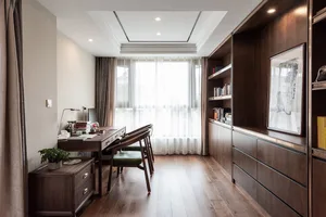 A modern office space featuring wooden furniture, a large window, and shelves filled with books.