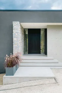 A modern residential entrance featuring a black door, concrete steps, and stone accents.