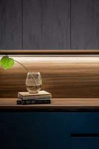 A green leaf in a glass vase placed on a stack of books, set against a wooden background.