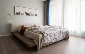 Minimalist bedroom featuring a bed with cotton and linen blend fabric on a wooden platform, with soft lighting and soft furni