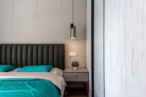 A modern bedroom featuring a upholstered bed with green bedding and a nightstand with a potted plant.
