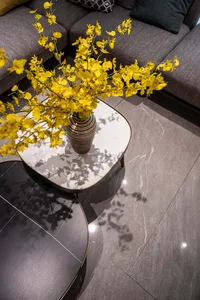 A modern coffee table adorned with vibrant yellow flowers in a sleek vase, placed on a marble surface.