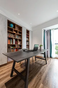 A modern home office featuring a wooden desk and floor-to-ceiling bookshelf.