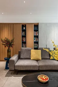 Modern minimalist living room featuring a gray sofa with yellow throw pillows, a black marble coffee table, and a wooden book