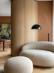 Modern minimalist living room with a circular sofa, ottoman, and abstract painting.