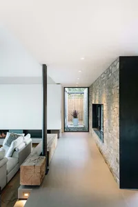 Modern living room with stone walls, concrete floor, and wooden accents