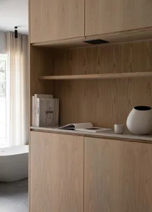 A minimalist interior space featuring wooden shelves and a bathtub with curtains.