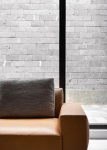 A modern industrial leather couch with a brick wall in the background.