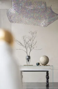 Minimalist interior featuring glass vase with white blossoms, marble table, and metallic decorative ball on a modern glass-to