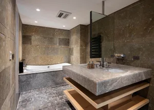 Modern bathroom with marble tile, sink, and bathtub, featuring a minimalist design.