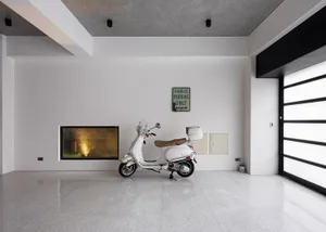 Modern industrial garage interior with minimalist design, featuring concrete flooring and a white Vespa scooter.