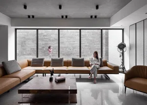A modern living room with a leather sofa, wooden table, and stone wall.