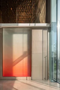 A modern lobby with a glass window featuring a red gradient shadow.