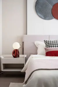 Modern minimalist bedroom featuring a bed with a soft fabric headboard, wooden floor, and a metallic bedside lamp.