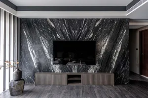 A minimalist living room featuring a black marble accent wall, dark wooden furniture, and a wooden floor.