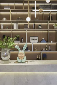 A modern reception desk made of marble with a rabbit figurine on top and decorative items arranged on the shelves in the back