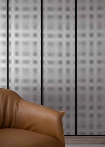 A modern sofa made of brown leather against a perforated metal wall in an industrial setting.