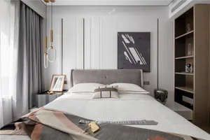 A modern minimalist bedroom with a white bed, grey headboard, and abstract wall art.