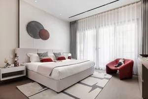 Modern minimalist bedroom featuring a bed with a fabric headboard and glass elements.