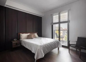 Minimalist bedroom with wooden walls and a white bed