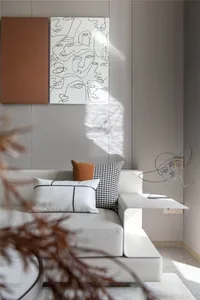 Minimalist living room with white leather sectional sofa, abstract art on the wall, and metallic sculpture on the side table.