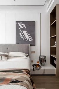 A modern bedroom featuring a bed with a fabric headboard, metallic vase, and wooden shelving unit.