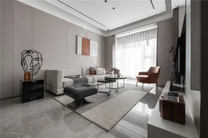 A modern living room with a gray tiled floor, featuring a white sofa, black ottoman, and minimalistic decor.