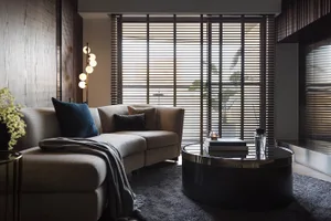 A modern living room featuring a beige sectional sofa with textured fabric and a concrete finish, positioned in front of a la