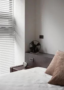 A minimalist bedroom with concrete furniture, a white bed, and brown pillows.