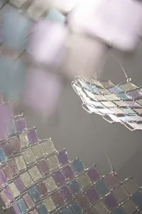 A modern art installation featuring glass and metal elements hanging in a gallery.