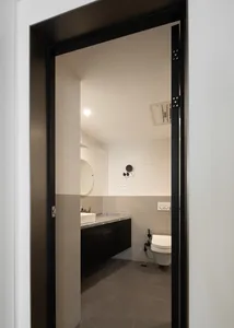 Modern minimalist bathroom with white tiled walls, marble countertop, and black accents.