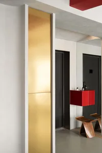 A minimalist residential interior featuring metallic elements, glass, and wooden furniture.