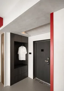 A modern entryway closet featuring concrete walls and a matte black finish.
