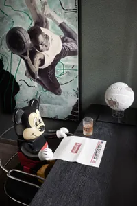 A modern minimalist interior featuring a black and white theme with a Mickey Mouse figurine holding a newspaper, a basketball