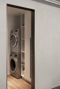 Modern minimalist laundry room featuring metallic appliances and sleek design.