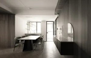 Modern residential dining room featuring wooden-paneled walls, a marble table top, and black furniture.
